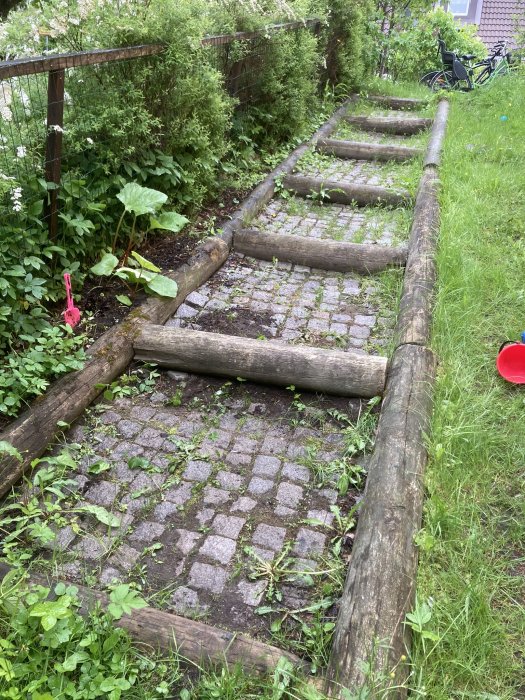 Trädgårdstrapp av stockar och stenplattor med synliga tecken på behov av underhåll.