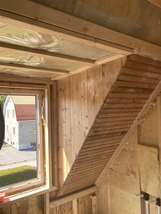 Pågående badrumsrenovering i takkupa med synlig trähårdvara och isolering.