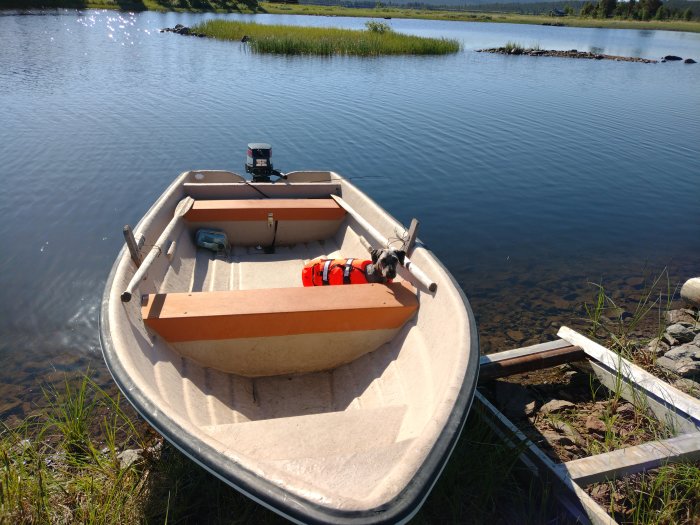 Motorbåt vid sjökant med hund ombord i Lapplands skärgård.