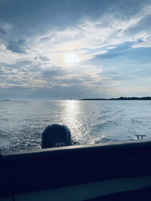 Vy från en båt med solnedgång över havet, skymning och en annan segelbåt i fjärran.