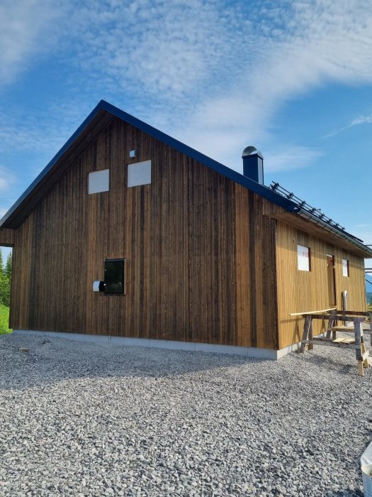 Nyligen färdigställd trägavel på hus med kaminrör "snorkel", byggställning och grusgrund.