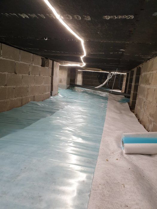 Nyinstallerad ångspärr i krypgrund med skurna och tejpade skarvar samt rulle med material.
