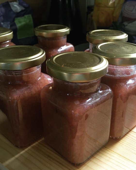 Burkar med hemgjord rabarbermarmelad på en träyta.