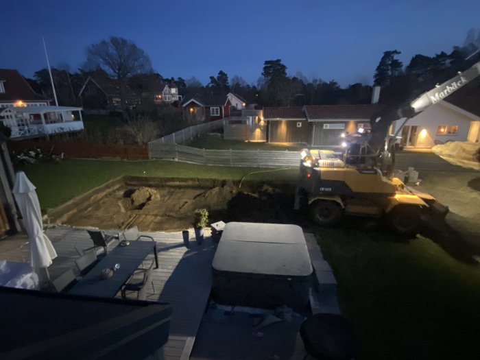 Nygrävd pool på en baksida i kvällsbelysning med grävmaskin och dumper.