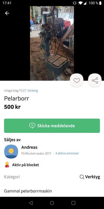 Gammal pelarborrmaskin i arbetsmiljö med diverse tillbehör och stålverktyg.