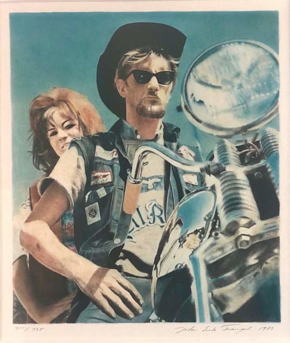 En man i solglasögon och hatt kör en motorcykel med en kvinna bakom sig.