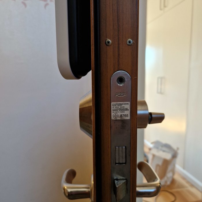 Låshus av märket Assa Abloy fast på dörr, utan synliga spännhål eller skruvar.