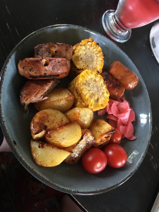 Tallrik med ugnsrostad potatis, grillspett, majskolv, chorizo, rädisor och tomater.
