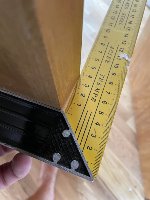 Vinkelkontroll på en dörrkant med en gul vinkelhake som visar att dörren inte är vinkelrät.