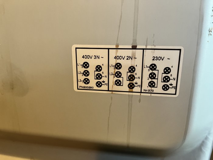Elektriskt kopplingsschema för 400V och 230V visar korrekt anslutning av kablar, fastsatt på en grå yta med synliga byglar.