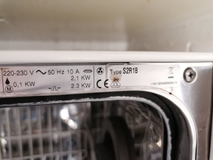 Typskylt på vitvaru med specifikationer 220-230V, 50Hz, 10A, 0,1-2,3kW och CE-märkning.