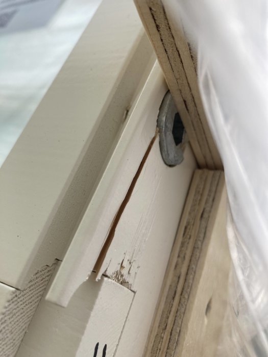 Närbild på ett fönster med sprickbildning vid karmhylsa nära smygspår.