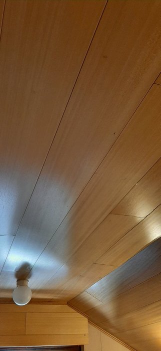 Trätak med synliga skarvar och en taklampa, behov av målningstips.