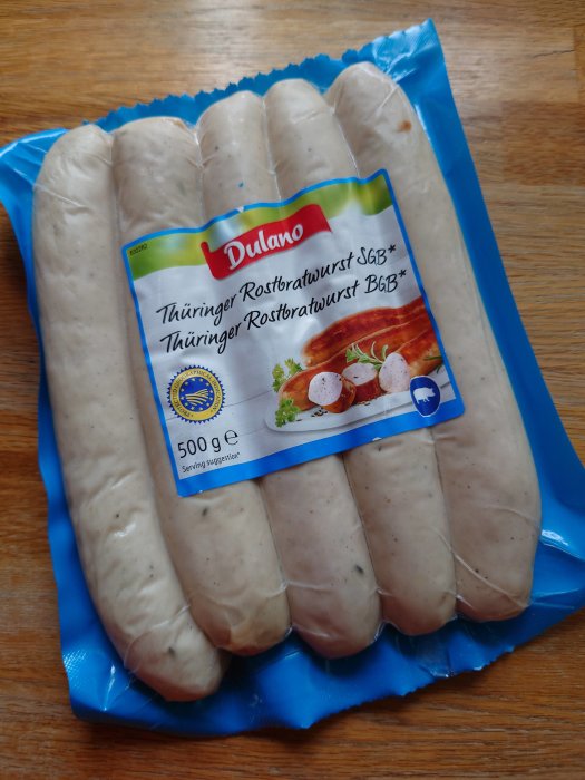 Förpackning med Dulano Thüringer Rostbratwurst korv på ett träbord.