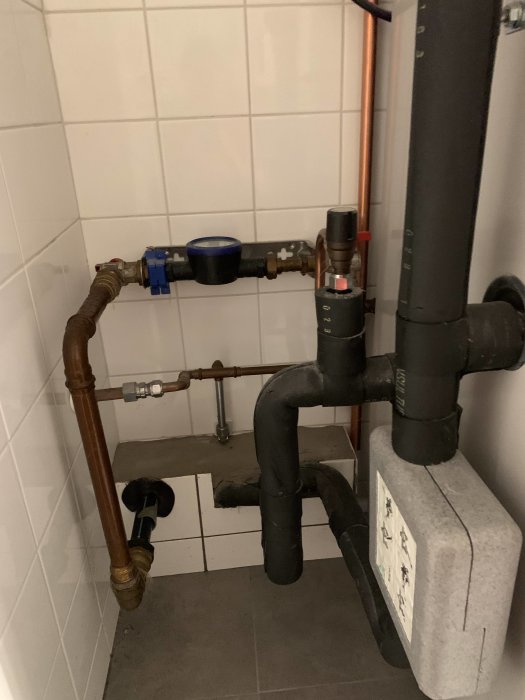 Vattenläckage vid rören i närheten av en bergvärmepump i en tvättstuga.