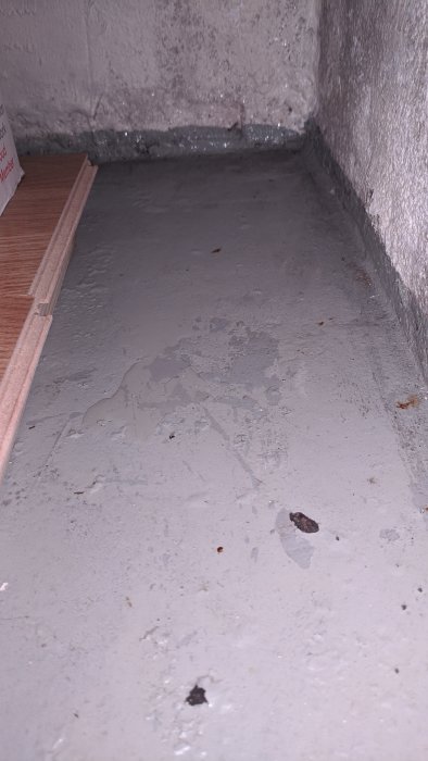 Fukt och kondens längs betongvägg och golv i källare.