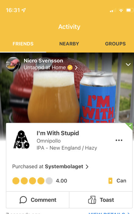 Ölglas med skummad öl brevid en ölburk med texten "I'M WITH STUPID" utomhus.