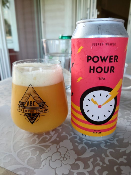 Ölglas med skum och burk av 'Power Hour TIPA' från Fuerst Wiacek, på blommönstrad duk.