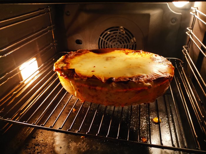 Hemlagad lasagne med gyllene yta gräddas i ugnen på ett galler.