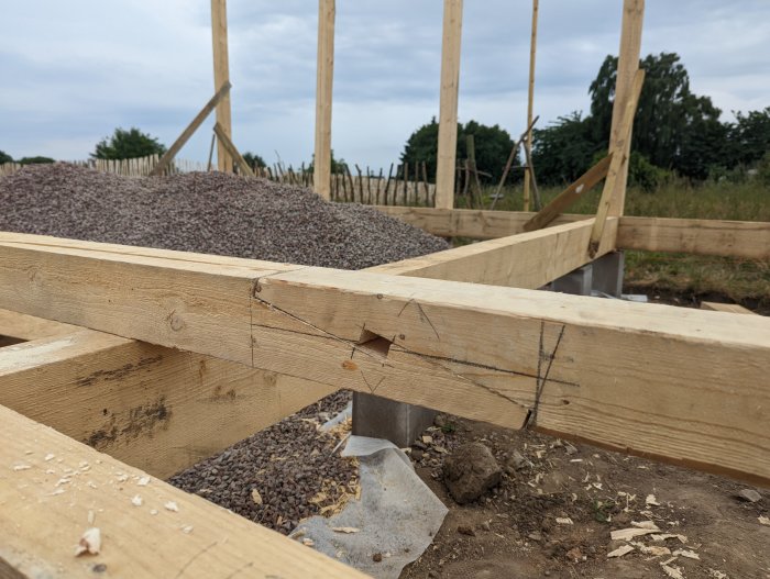 Blixtskarv i hammarband på byggprojekt, markerad och delvis bearbetad träkonstruktion i förgrunden, med konstruktionsdetaljer i bakgrunden.