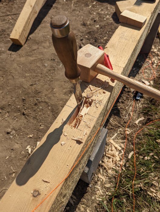 Träbearbetning med tapphål och hörntapp i träkonstruktion, verktyg och spån synliga.