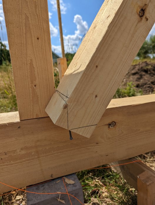 Snedsträva fixerad vid träramverk med utritad linje för kapning och en tapp i förgrunden.