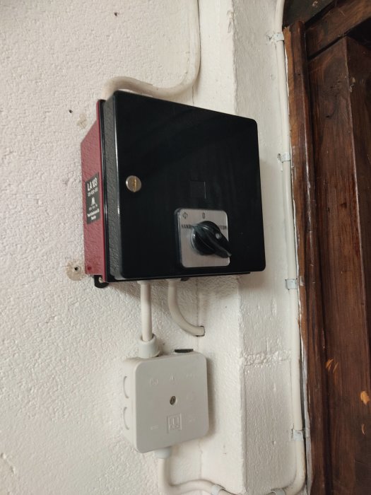 En gammal brytare med vredet inställt på "på" monterad på en vägg ovanför en ljussensor.