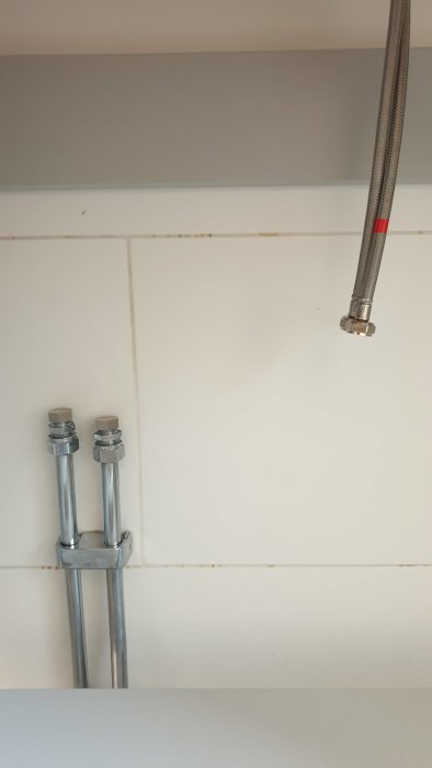 Installation av ny blandare, kulventiler och flexslang som inte når fram på vit kakelvägg.