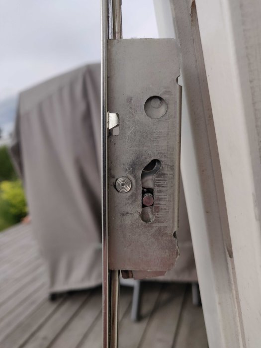 Närbild av en öppen altandörrs spanjolett som inte hakar i, synliga mekaniska delar.
