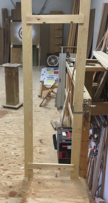 En tillfällig träram representerar en dörrs placering i en verkstad med verktyg och byggmaterial.