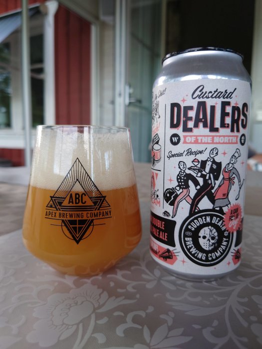 Ölglas fyllt med hazy ale bredvid en burk märkt Custard Dealers of the North på ett bord.