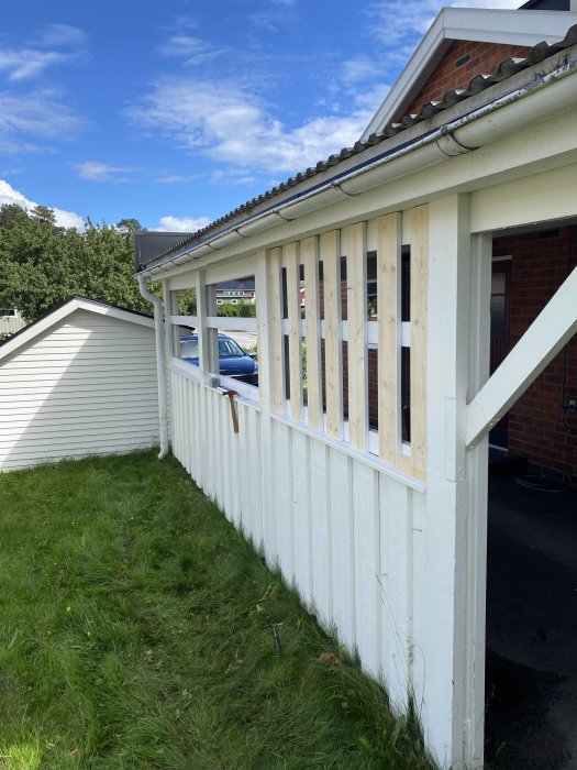 Pågående arbete med att bygga igen en carportöppning med träreglar på en vitmålad carport.