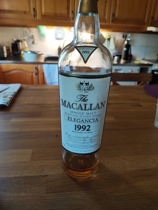 Öppnad flaska MacAllan Elegancia 1992 whisky på ett köksbord.