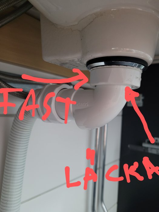 Vattenlås under handfat med en markerad läcka och texten "FAST" och "LÄCKA" på bilden.