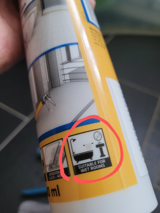 Ett rör av tätningsmedel nära där etiketten visar "Suitable for wet rooms" med handfat och duschsymboler.