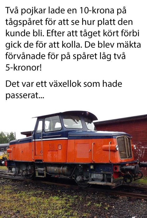 Ett orange lok på ett järnvägsspår med en textskylt om platta mynt framför.