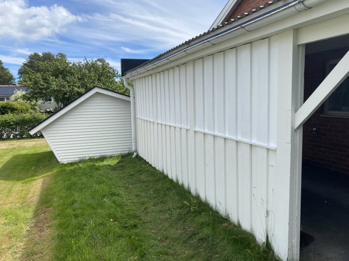 Vit träpanel på en carport vid hus med gräsmatta, redo för installation av downlights.