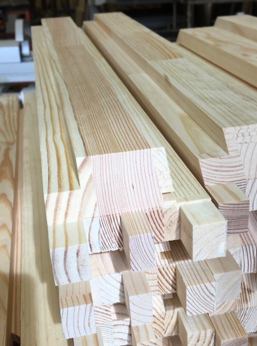 Staplade trälistar med färdiga tappar och sågade falser redo för användning i fönstertillverkning.