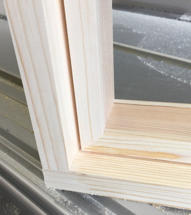 Närbild på nysågade träprofiler med falser för glasinfattning, täta hörn och sågspår för tätlist.