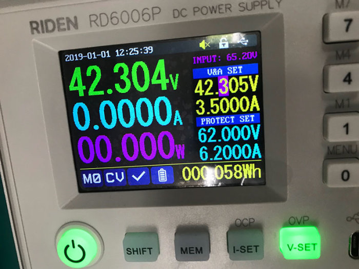 Digital skärm på ett labbaggregat som visar en utspänning på 42.304V och 3.500A, inställd för att ladda en robotklippare.