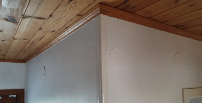 Hörn av en hall med träbjälkar, vägg med en kopplingsdosa, elcentral och vägguttag.