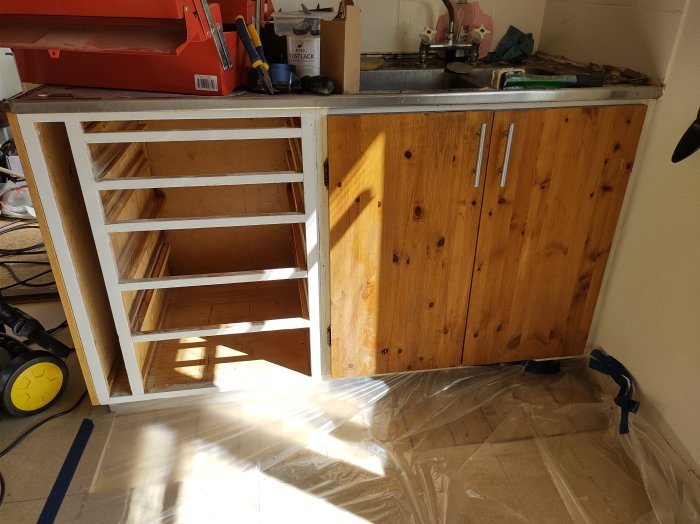 Gammalt köksskåp utan dörrar redo för installation av en smal diskmaskin.