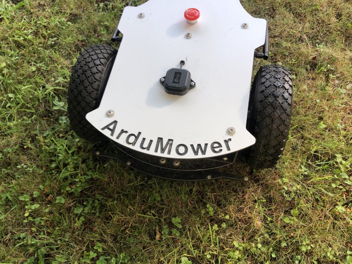 Moddad ArduMower robotgräsklippare med omönstrade däck och tyngdpunkten bakom axeln, på gräs.