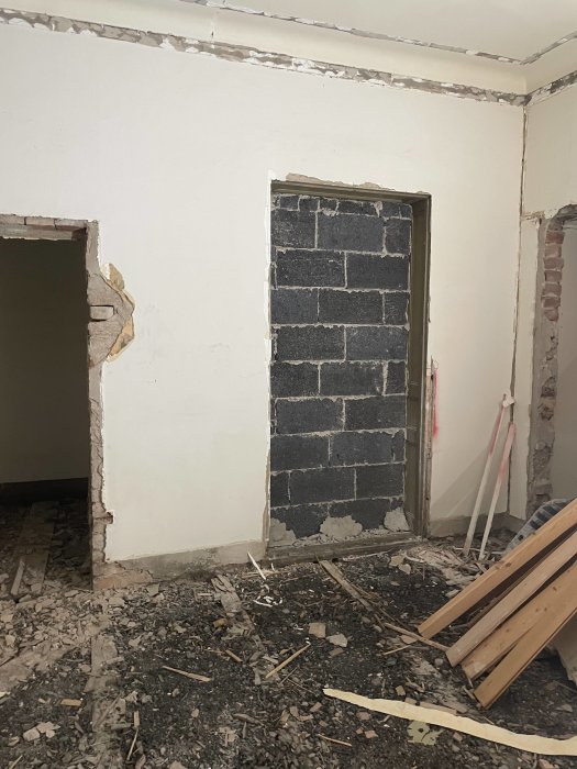 Igamlat entréutrymme med murade gråsvarta block, möjligen blåbetong, under renovering.