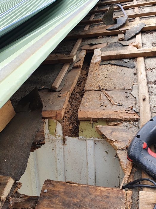 Öppnat tak visar rutten taktass och råspont, arbete pågår för att ersätta skadade delar.