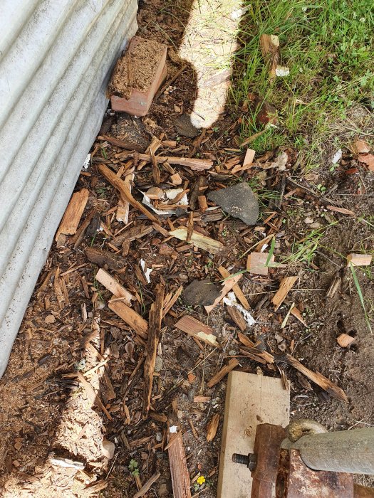 Rutten trä och spillror från ett byggtak ligger på marken bredvid, indikerar reparation av taktass.