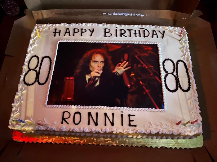 Födelsedagstårta med texten "Happy Birthday", namnet "Ronnie", siffran "80", och en bild på en man.