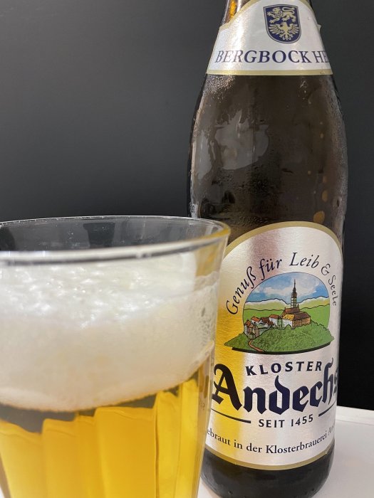 Flaska av Kloster Andechs öl med etikett och ett halvfullt glas öl framför.