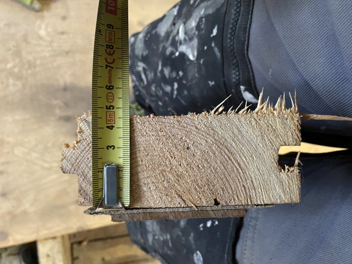 Mätning av tjockleken på ett gammalt trägolv med tumstock, tjocklek cirka 4,5 cm.