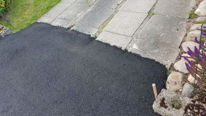 Asfalterad kant bredvid en trottoar där gammalt och nytt möts ojämnt.